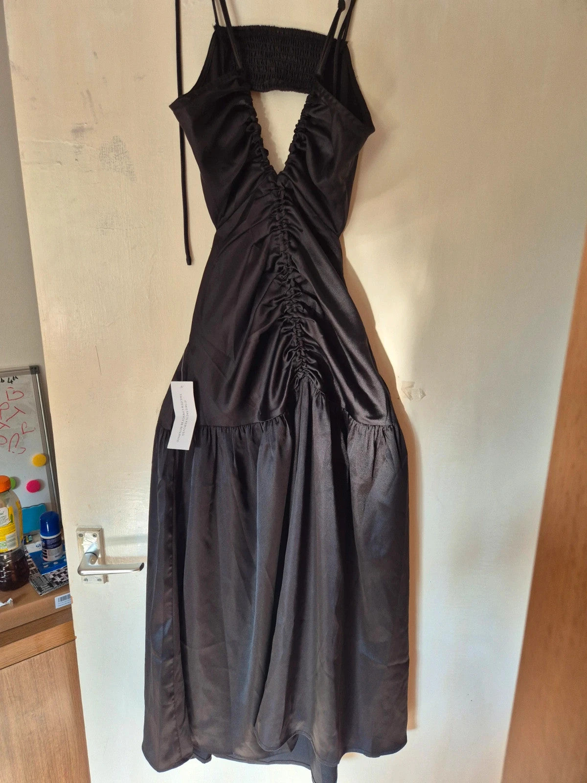 Amy Lynn black coat with satin sheen, ruched detailing, and plunge V-neckline.